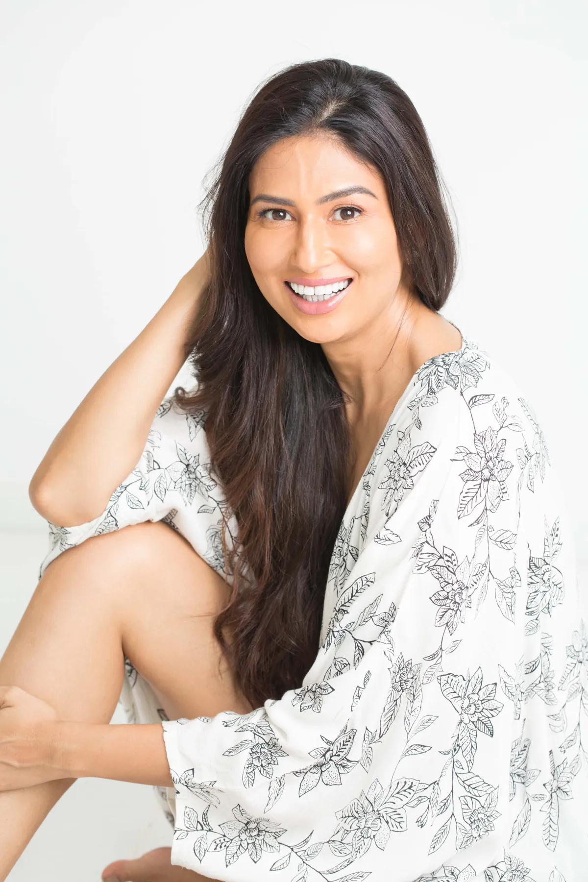 Uma Ghosh smiling, seated in a white studio