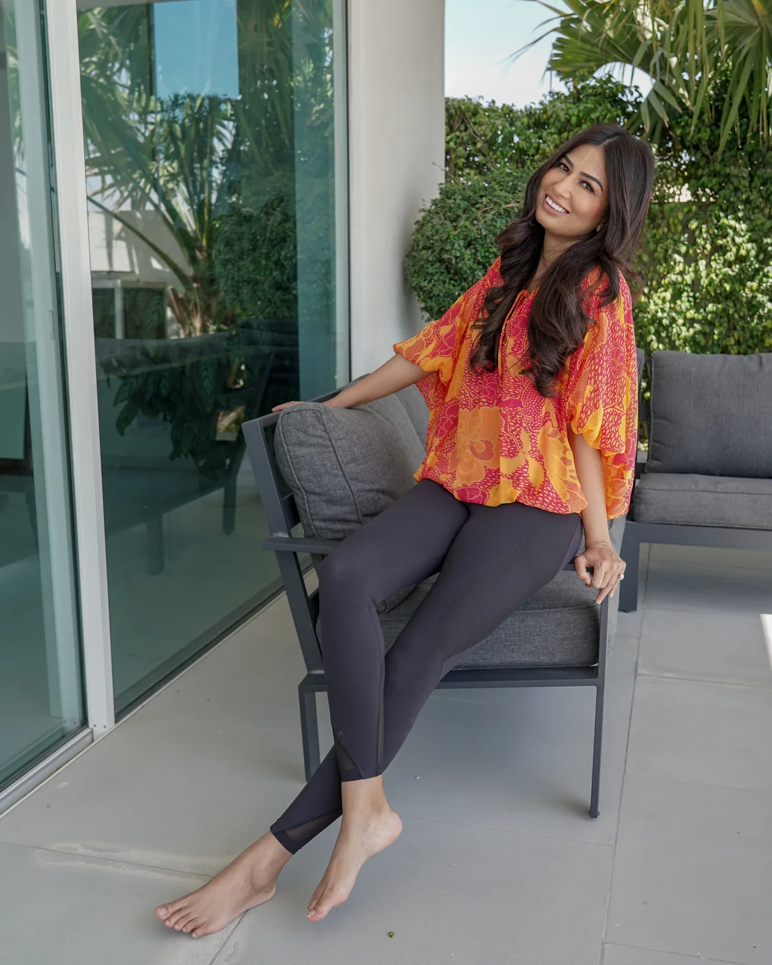 Uma Ghosh seated on a garden sofa by the glass doors