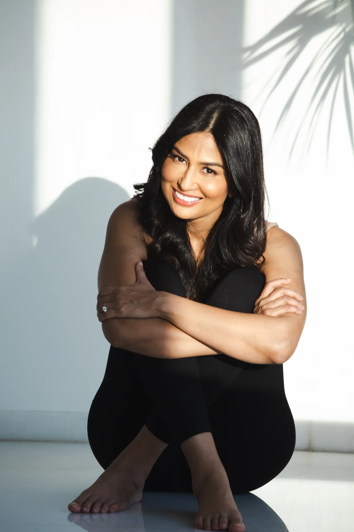 Uma Ghosh smiling, seated with her arms around her knees