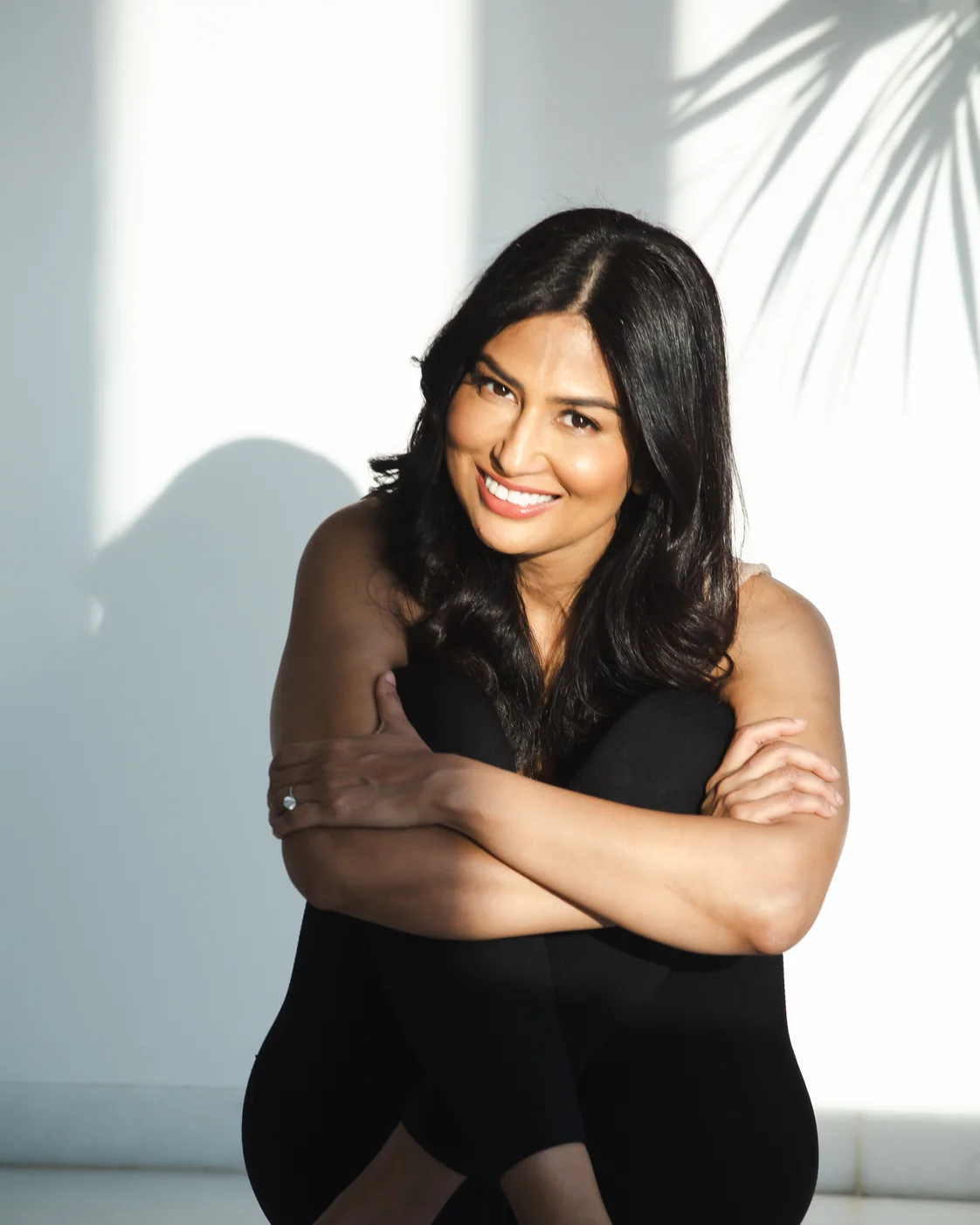Uma Ghosh smiling, seated on the floor at home