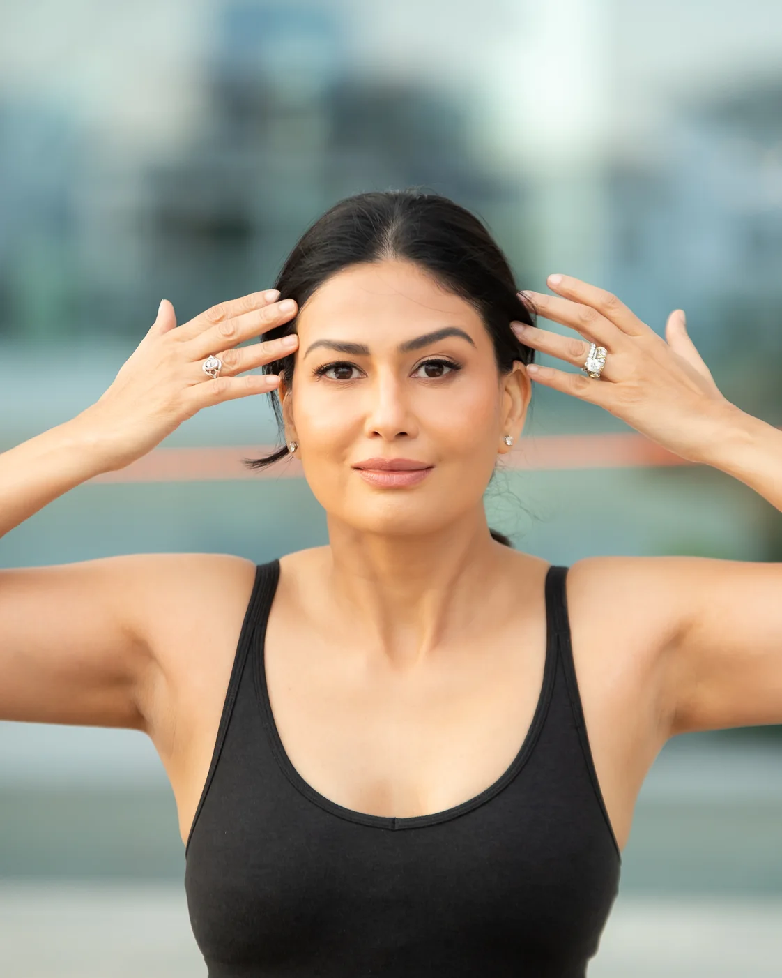 Uma demonstrating fingertip placement at her temples and brow