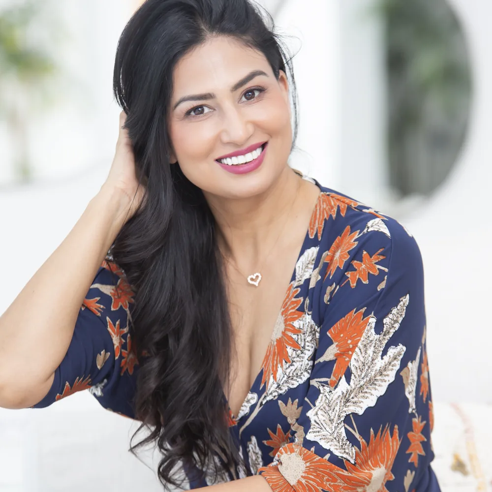 Uma Ghosh smiling, one hand resting in her hair