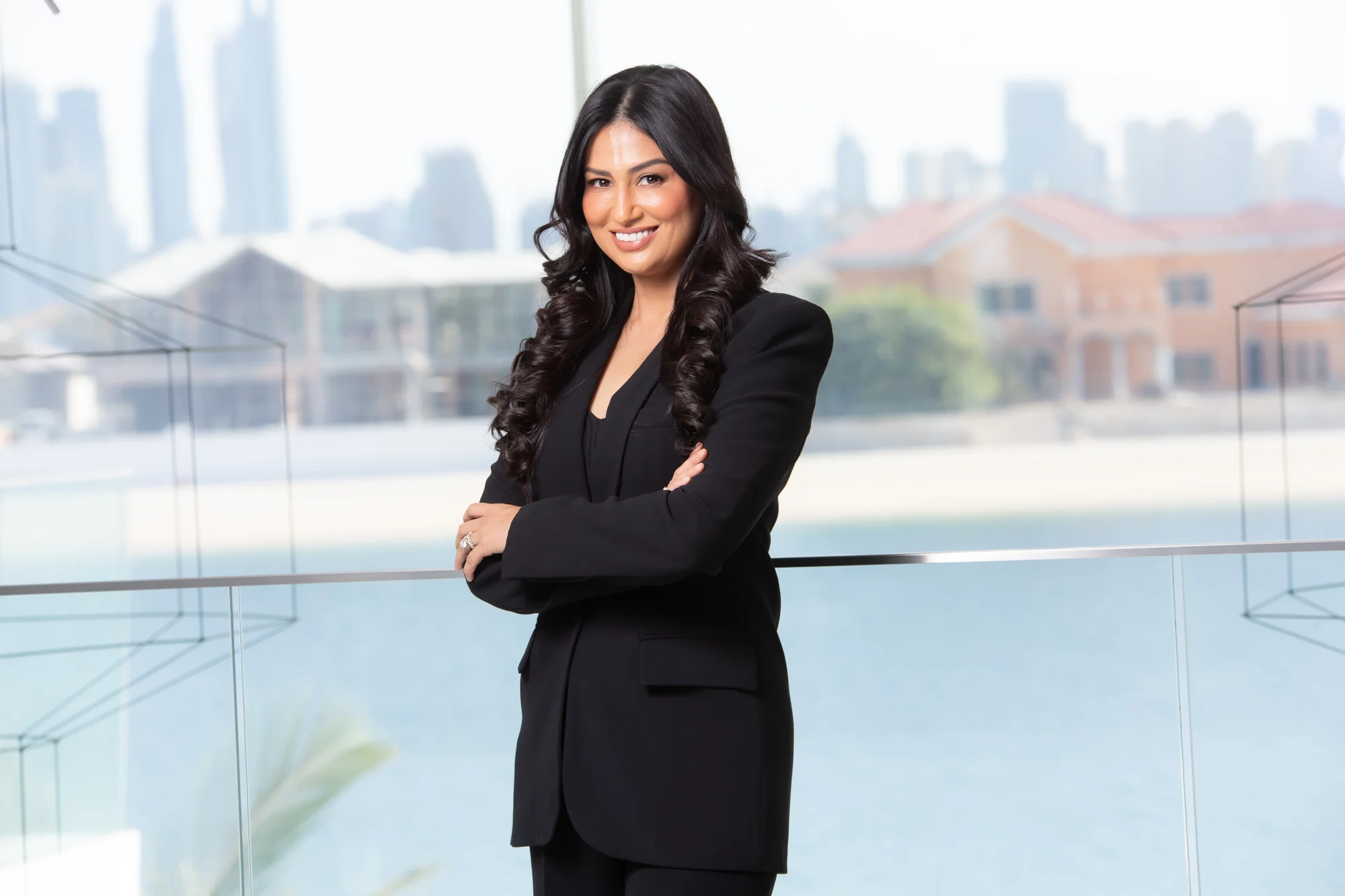 Uma Ghosh in a black suit with the Dubai skyline behind her