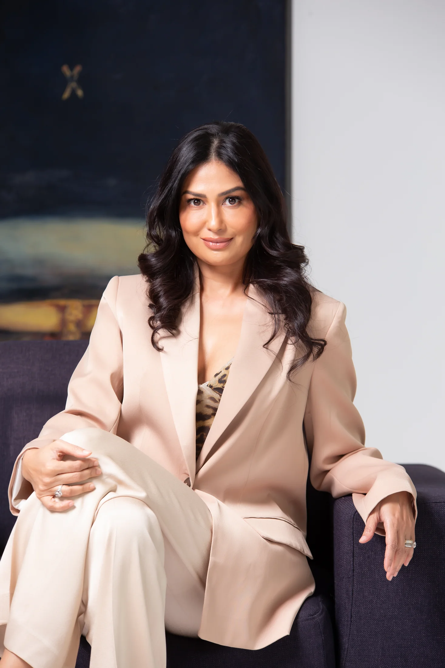 Uma in a tailored blush suit, seated in a formal portrait