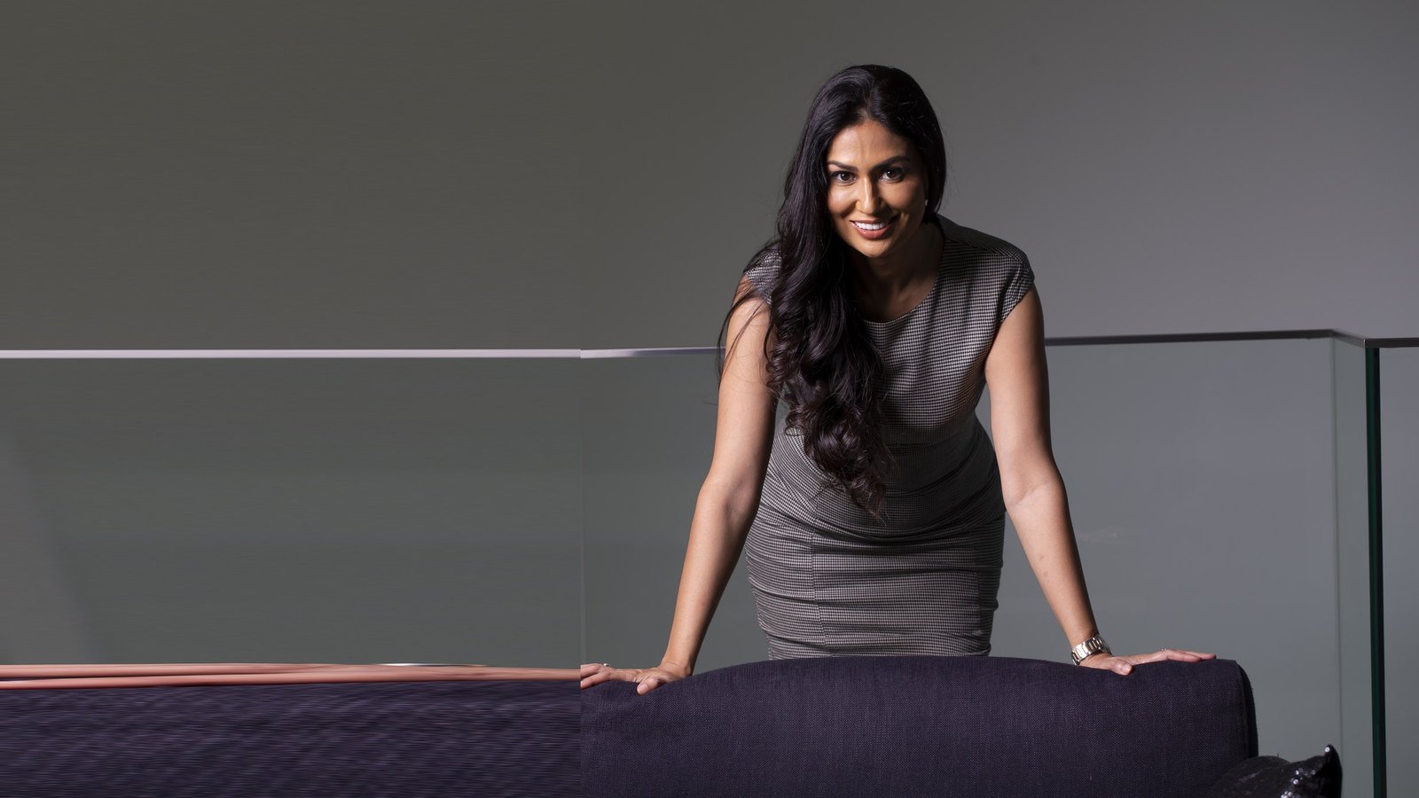 Uma Ghosh standing in a bright meeting space, smiling towards the camera