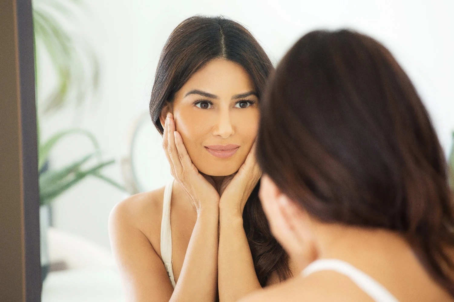 Uma looking at her skin in a mirror
