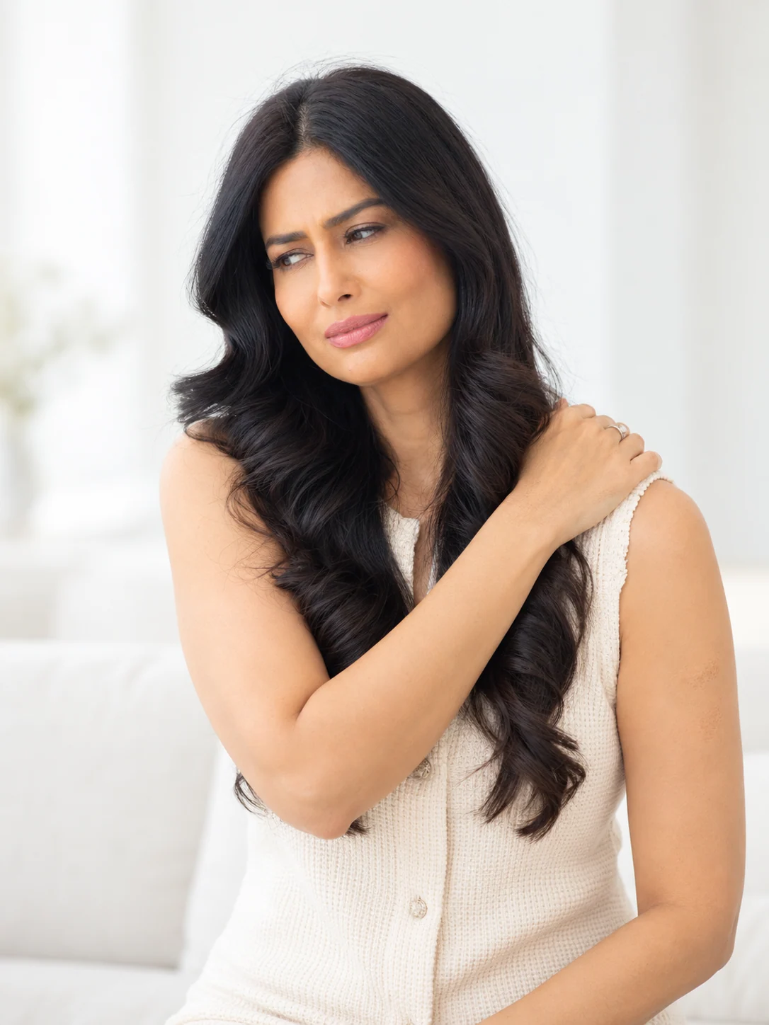 Uma holding her upper shoulder with a small incline of her head and an expression of tension